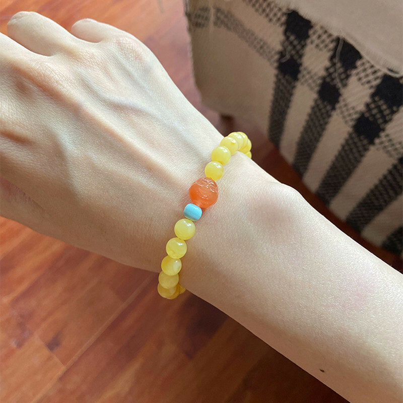A simple, fashionable and elegant women's amber bracelet with a turquoise red Buddha head is available for one-piece delivery