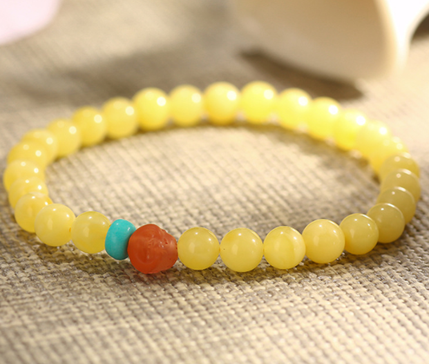 A simple, fashionable and elegant women's amber bracelet with a turquoise red Buddha head is available for one-piece delivery